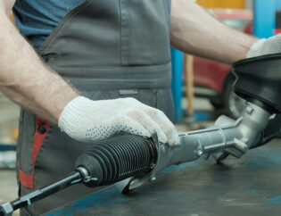 mechanic handles a power steering rack and pinion assembly